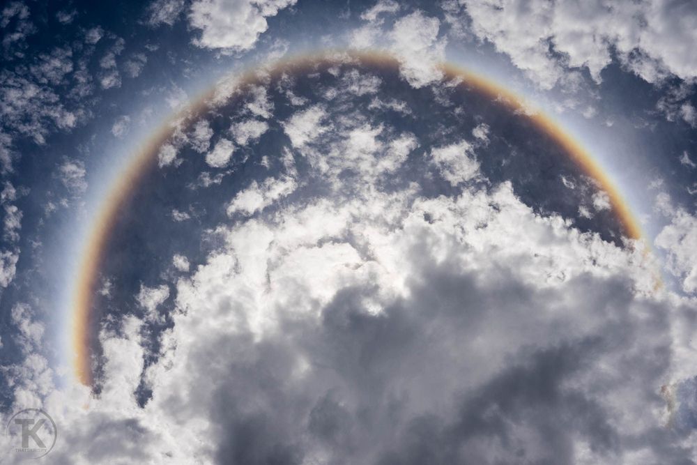 Circular rainbow halo forming around clouds