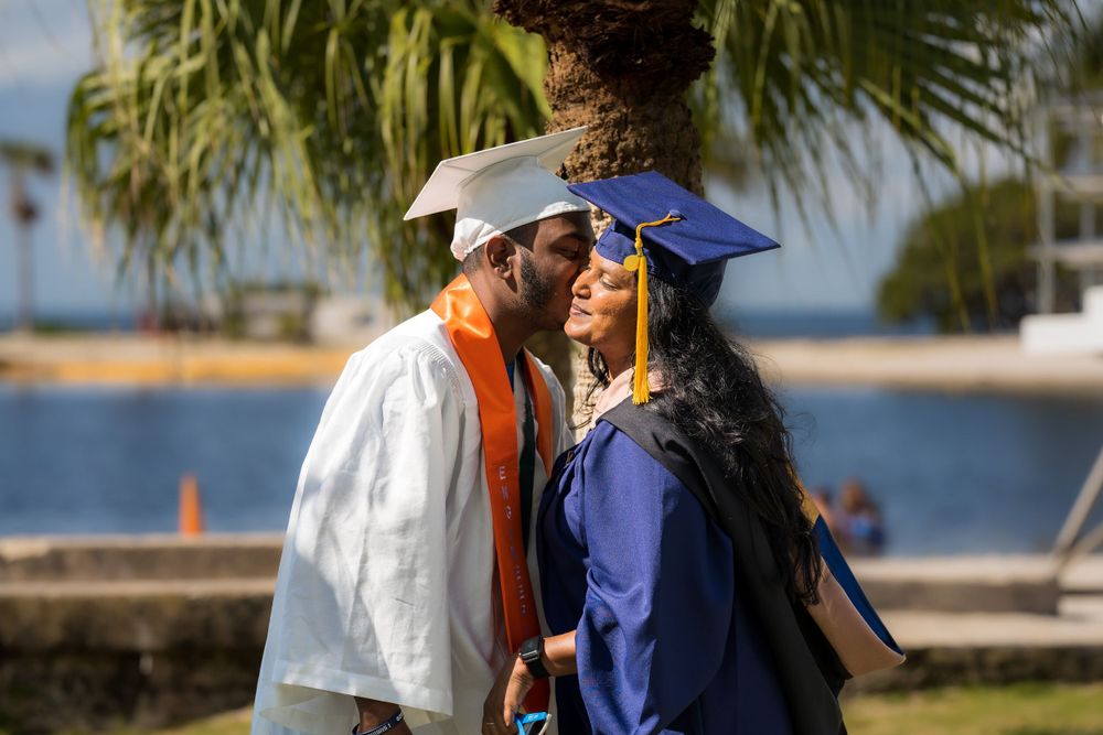 Graduate in cap and gown embracing a loved one at the waterfront
