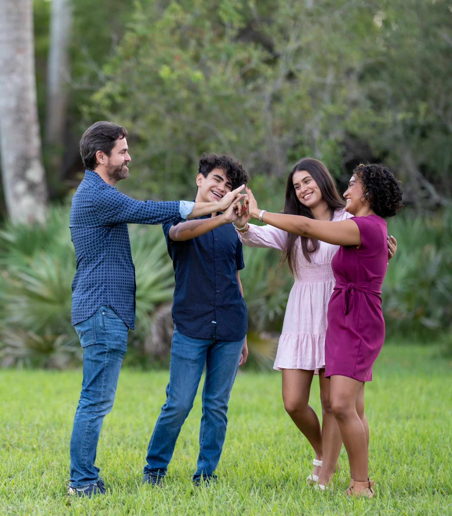 A family of four joining hands together on the grass