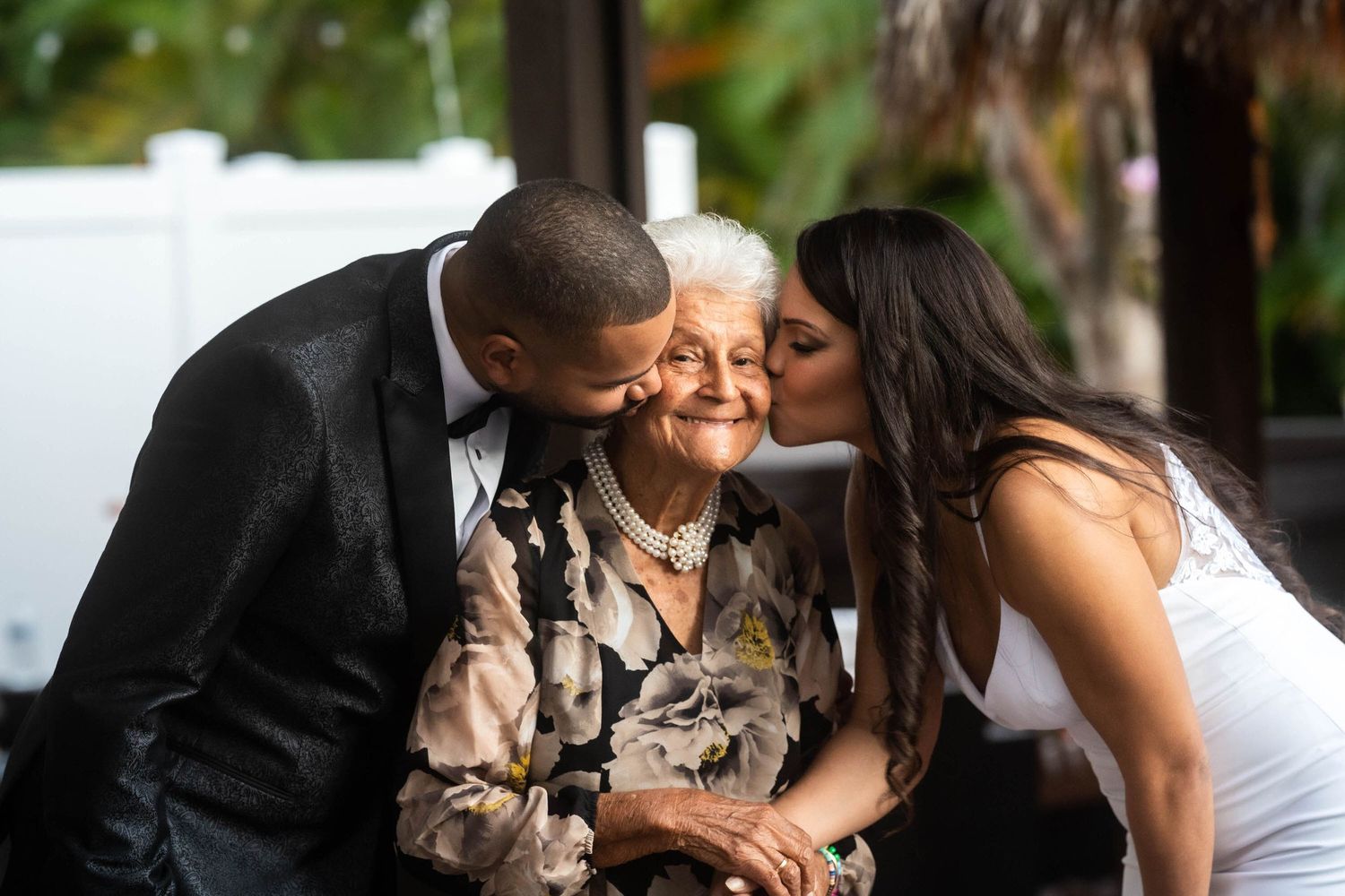 Bride and groom kissing an elderly guest on both cheeks at the reception