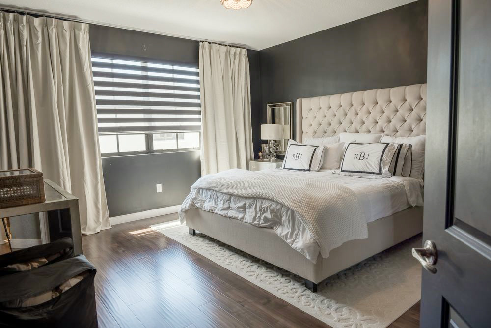 Primary bedroom with a dark accent wall and a tufted upholstered headboard