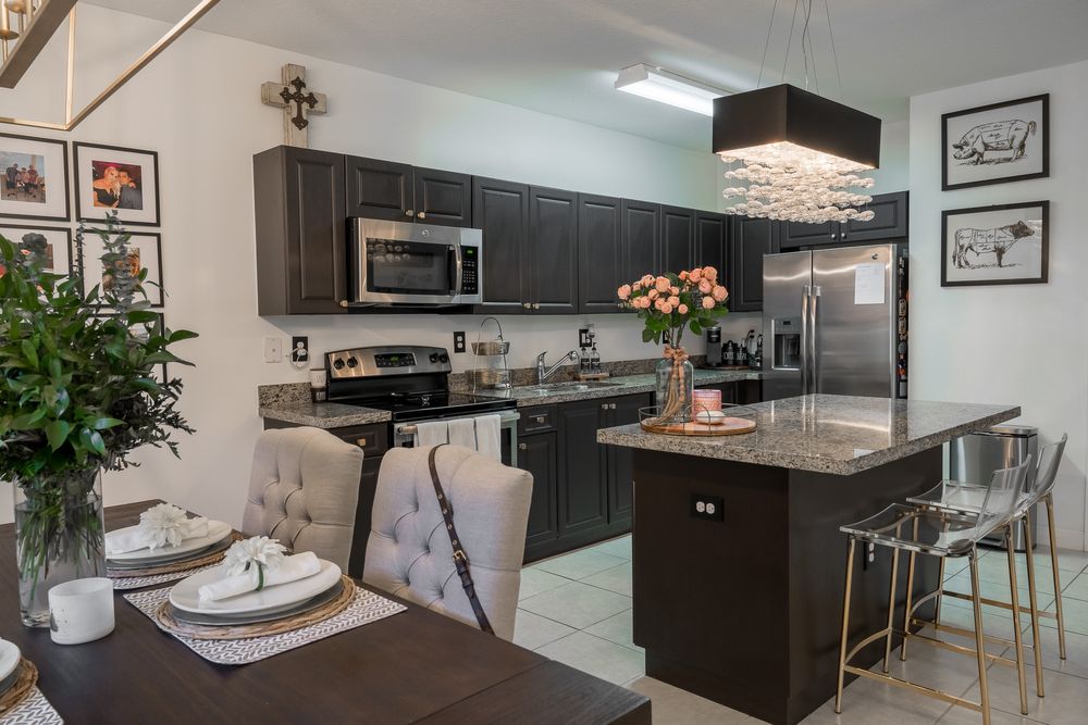 Kitchen and dining area with dark cabinetry, a granite island and a set table