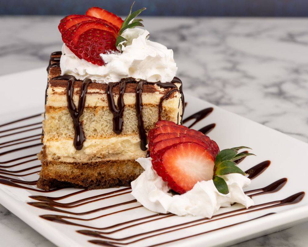 Slice of cheesecake with strawberries and chocolate drizzle