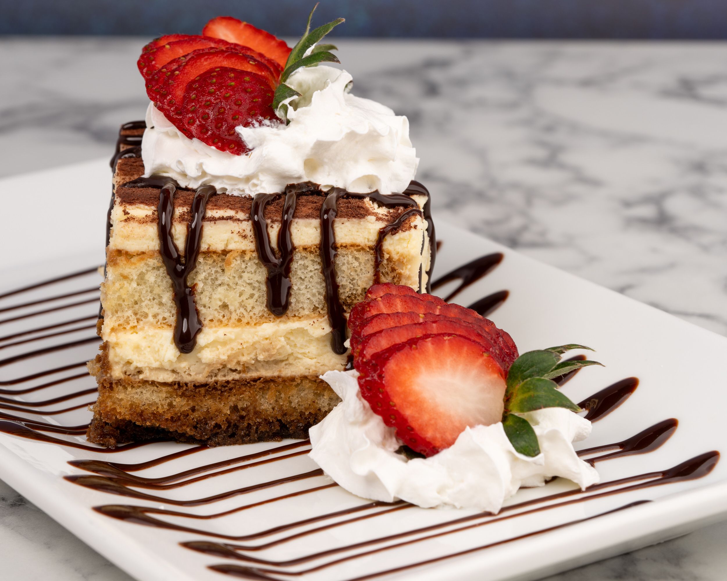 Slice of cheesecake with strawberries and chocolate drizzle