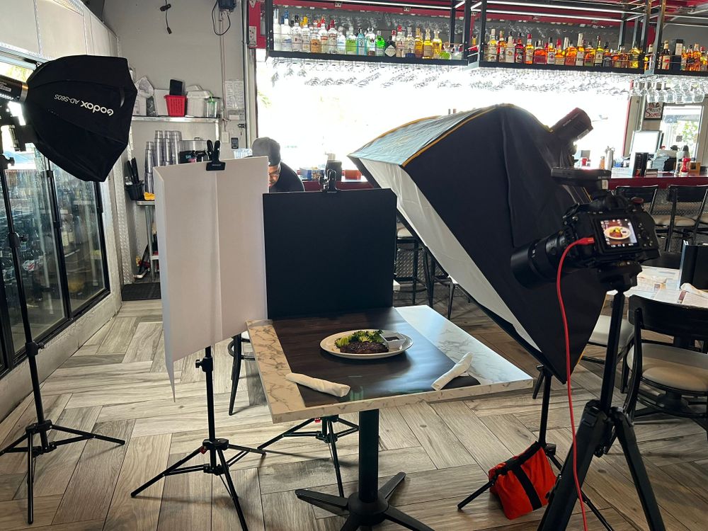 Lights and a camera set around a dining room table for a combined photo and video shoot