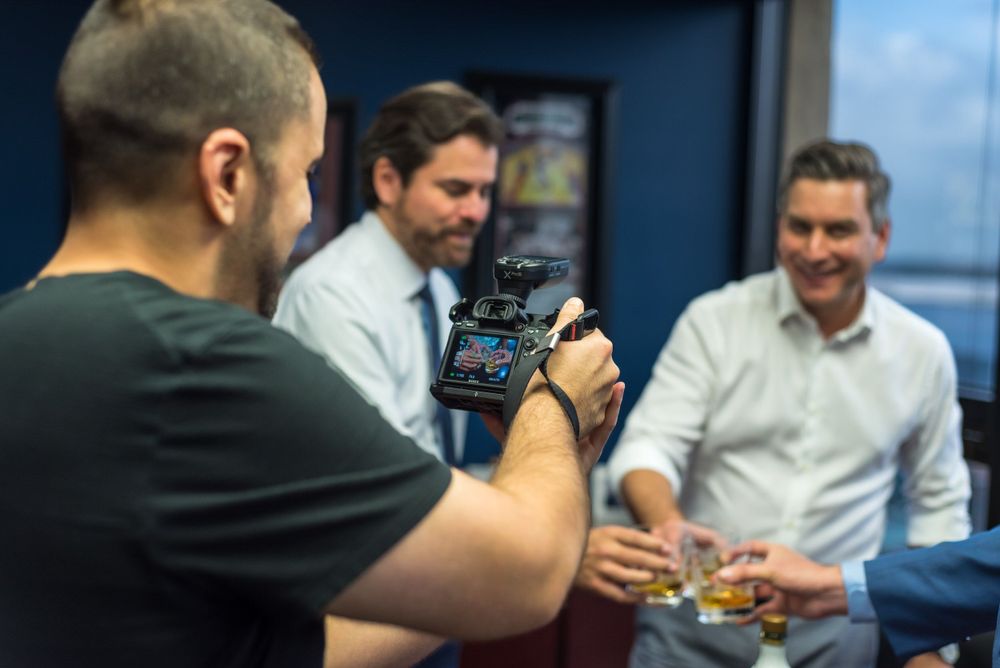 Camera monitor showing a close-up shot of two people toasting drinks at an event