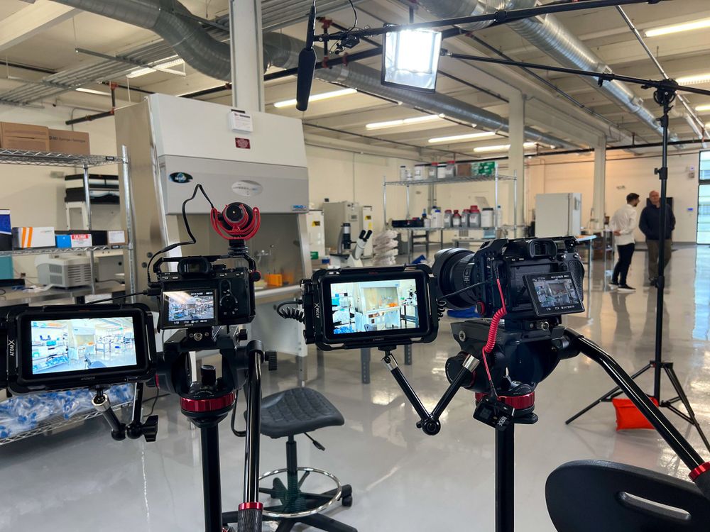 Three camera rigs with monitors lined up across a lab floor