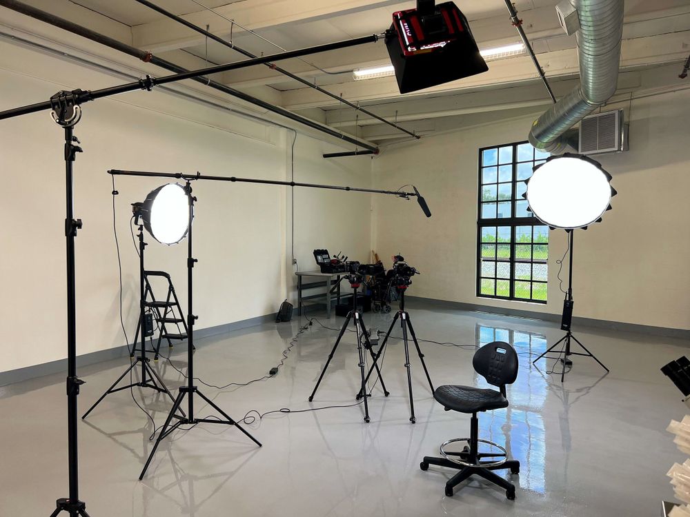 An empty studio set with boom lights, stands and a stool, lit and ready for an interview