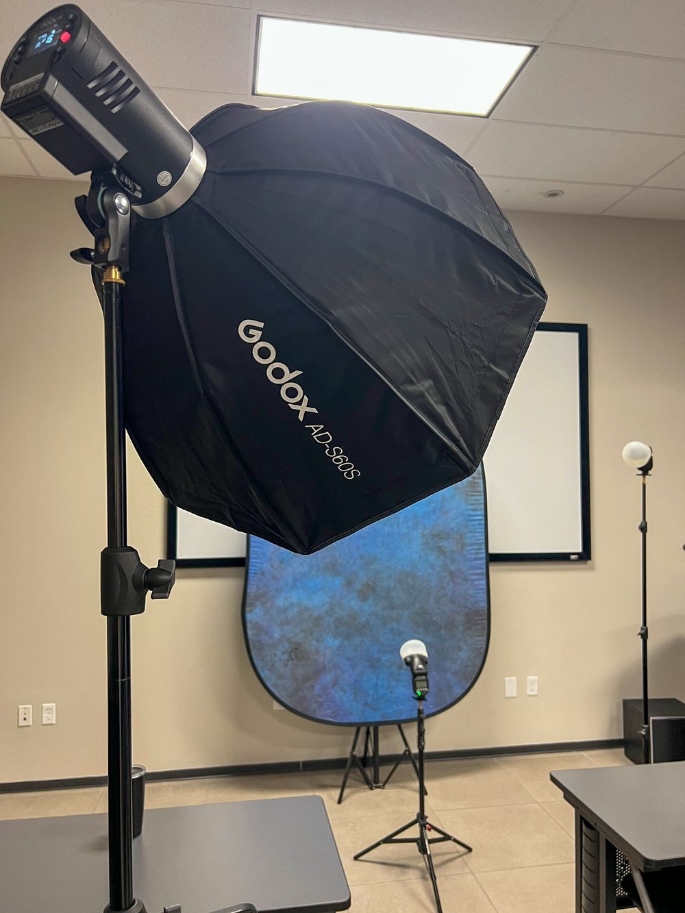 A softbox and a blue portable backdrop set up in an office for an interview