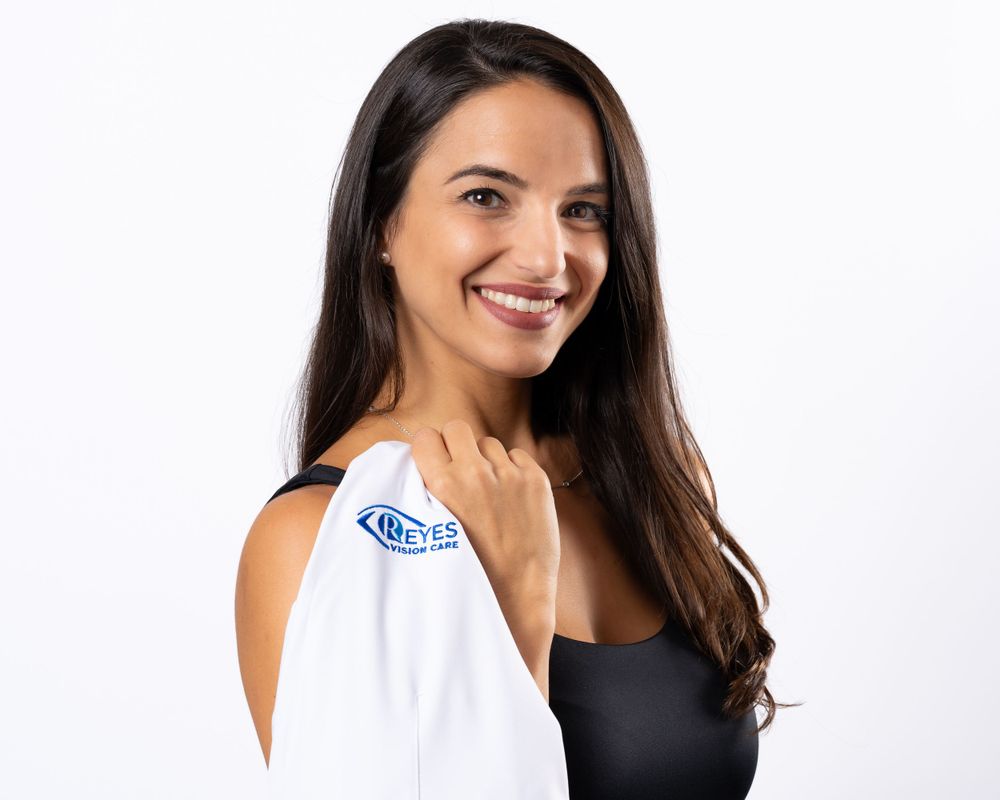 Studio headshot on white, woman with long dark hair and a white coat over her shoulder
