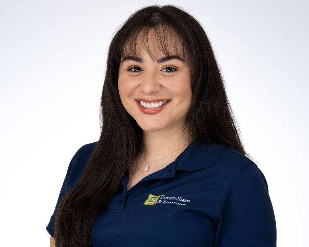 Studio headshot on a soft gray backdrop, smiling woman with bangs and a navy polo