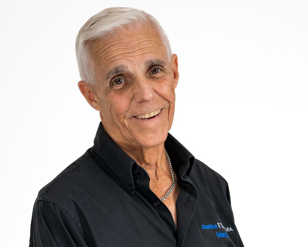 Studio headshot on white, silver-haired man in a black shirt
