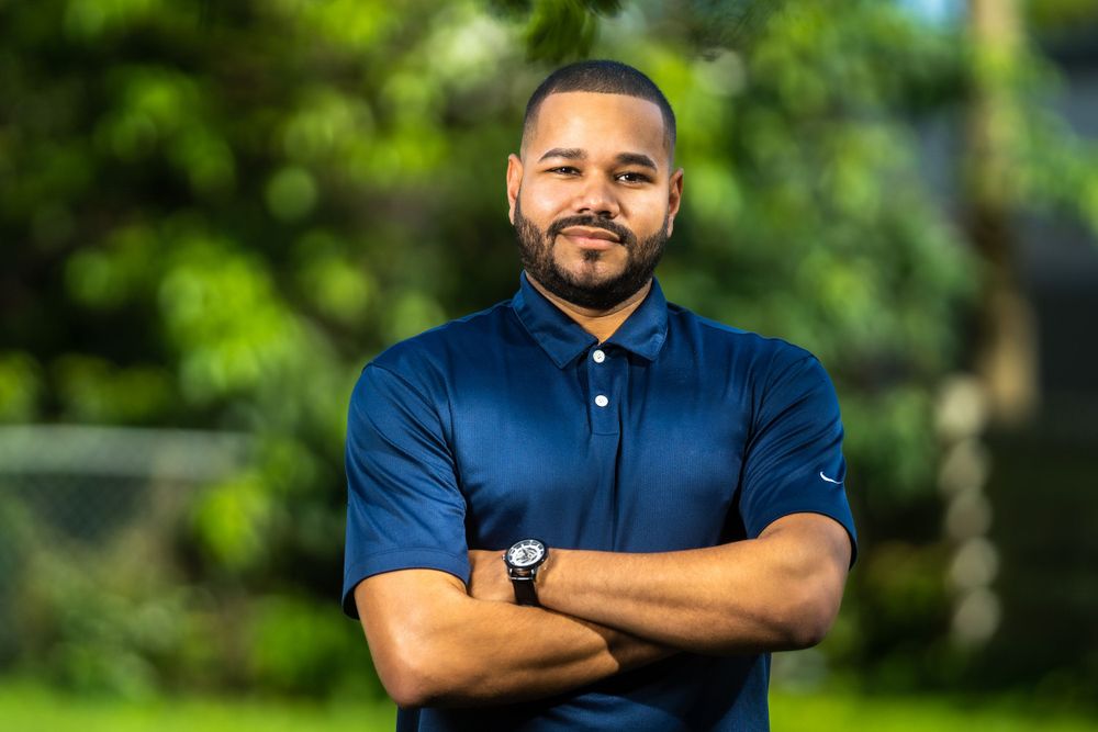 Outdoor headshot in natural light with green foliage in the background
