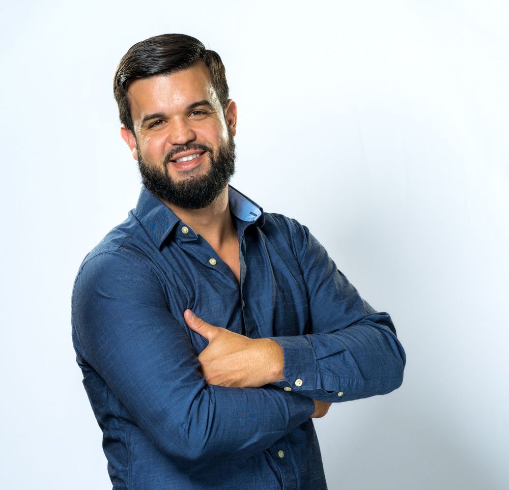 Studio headshot on white, arms crossed, navy button-down shirt